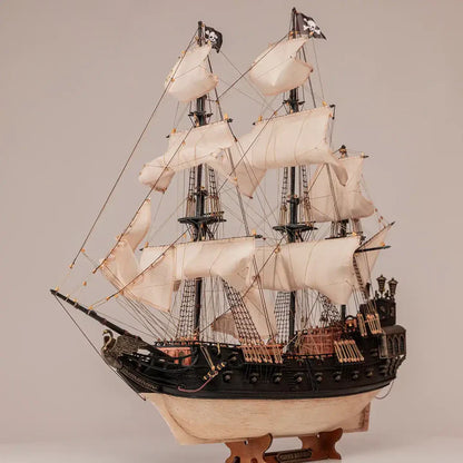 OcCre Black Swan 12012 wooden pirate ship model displayed with its complete sailing rig, dark hull, decorative stern and detailed deck structures.